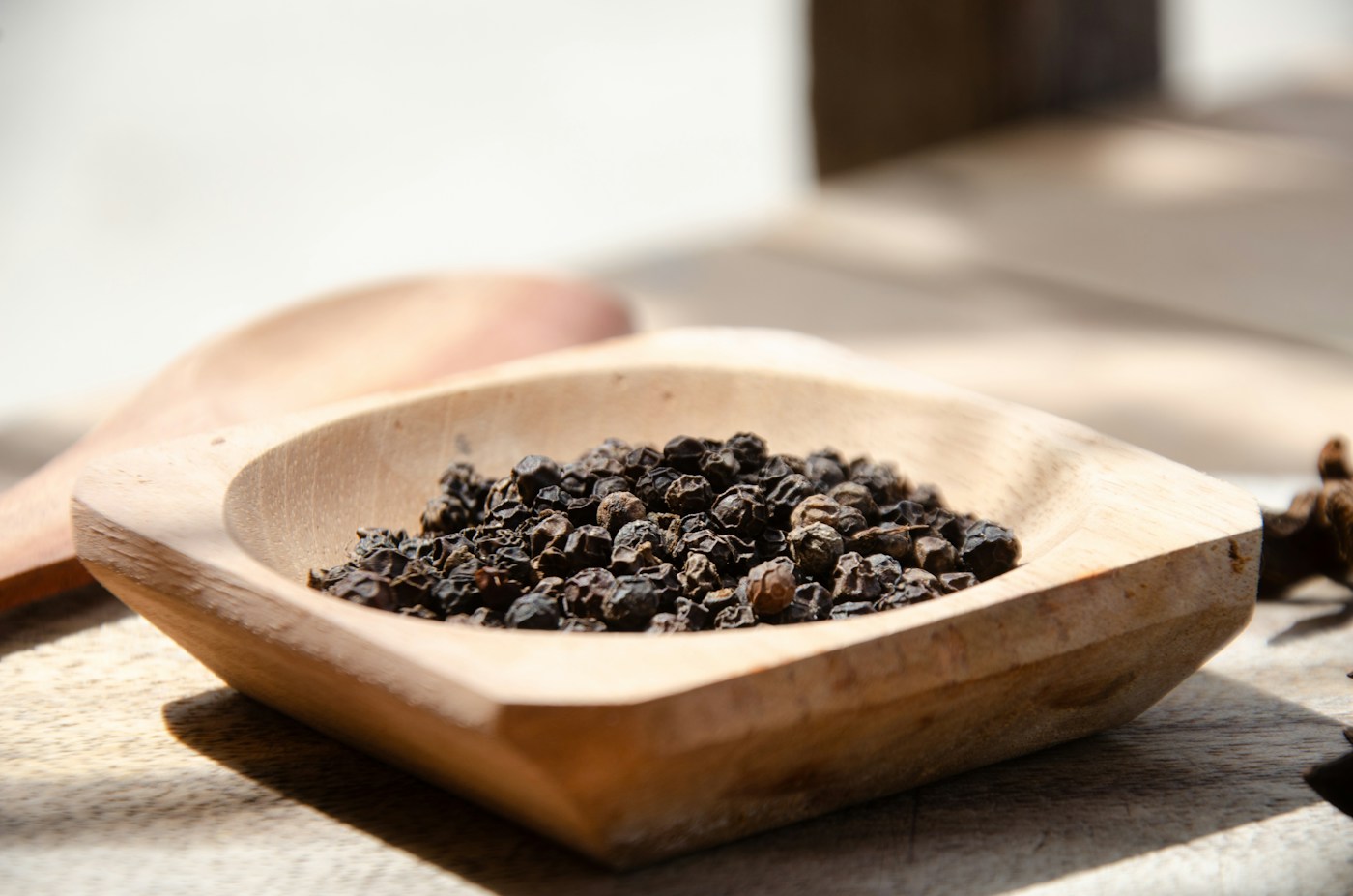 Butiran lada hitam dalam mangkuk kayu